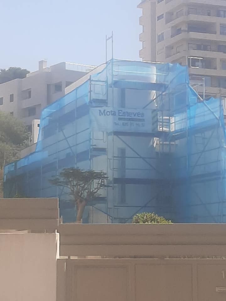 Esquina de edificio con red y cartel de la empresa